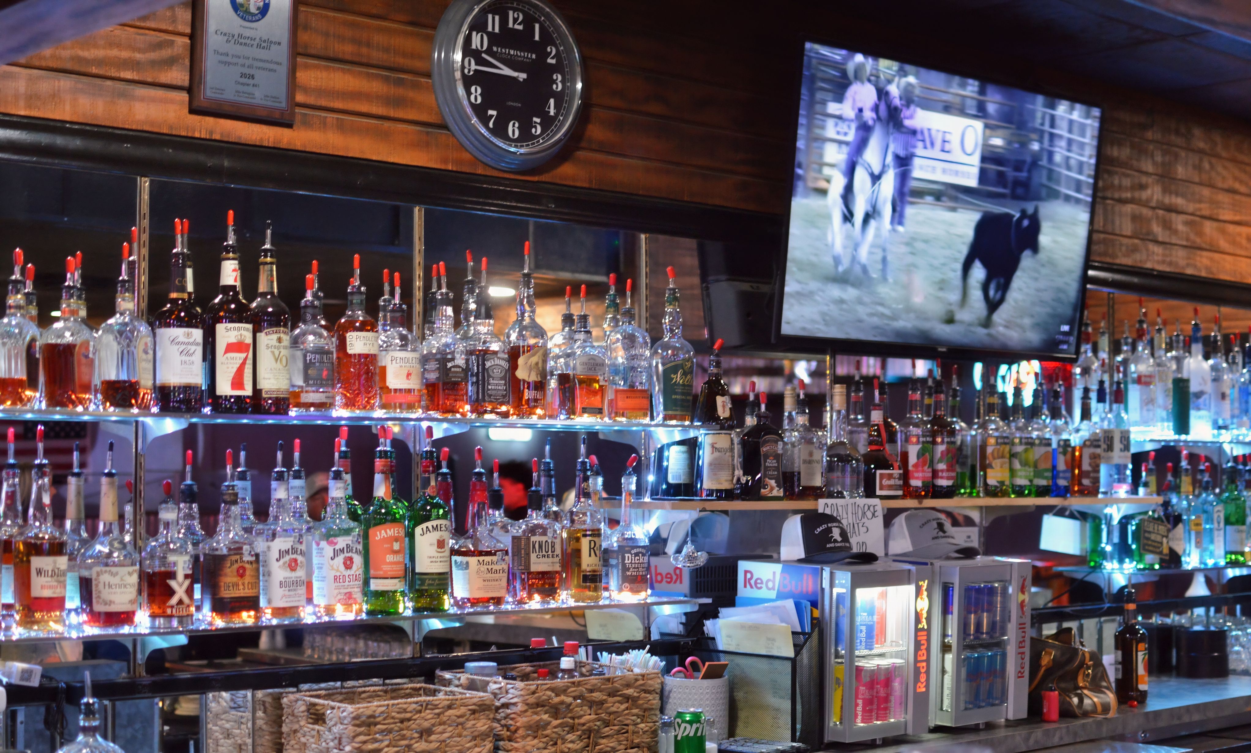 Front bar at Crazy Horse Saloon with neon signs and a lively crowd