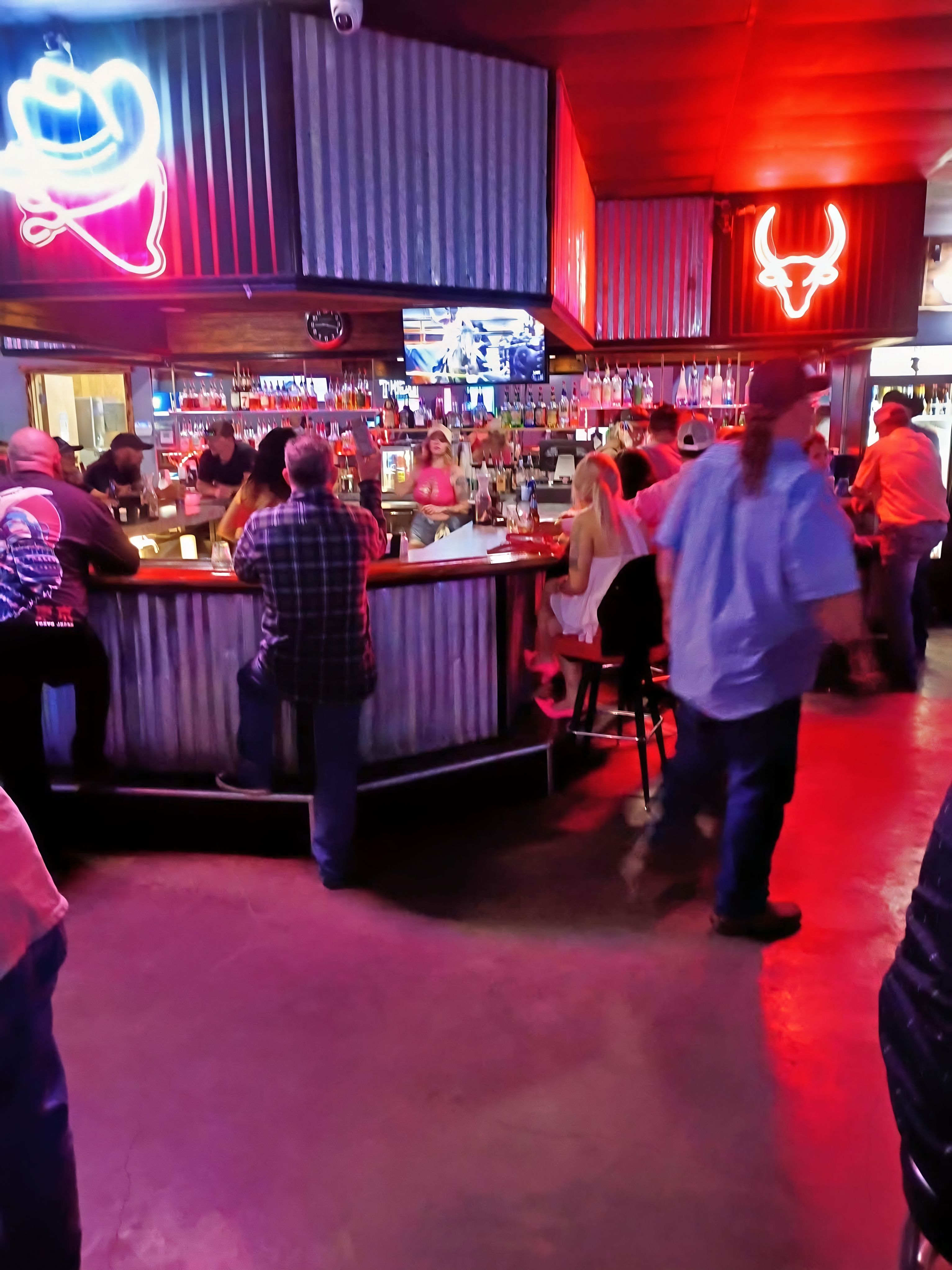 Front bar at Crazy Horse Saloon lit up with neon signs and a packed crowd